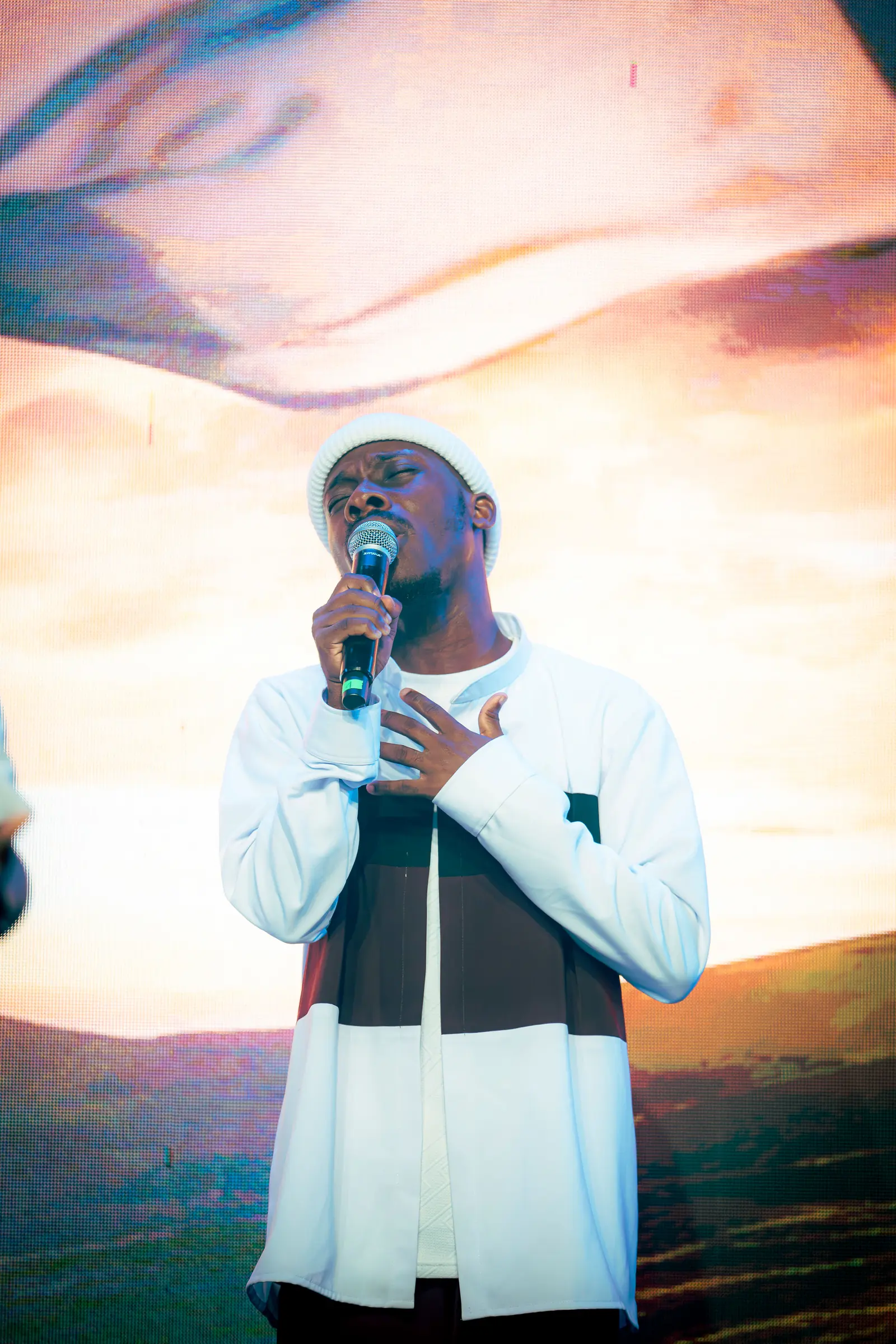 Paddy Daniel singing against a glowing sunset backdrop