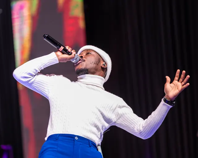 Paddy Daniel singing with arm outstretched in a white sweater