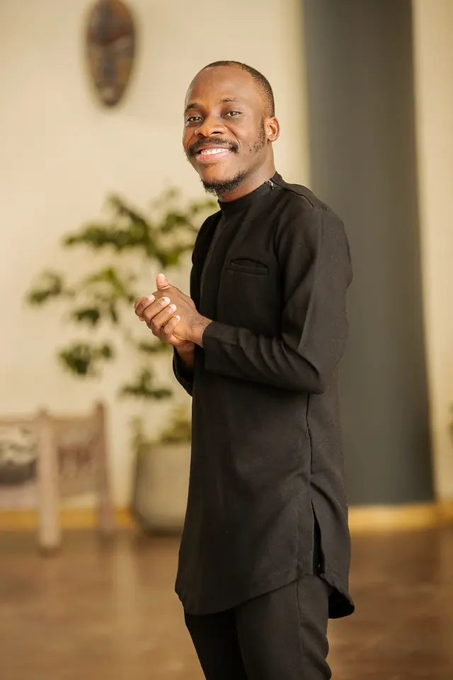 Paddy Daniel in a black kaftan, looking to the side