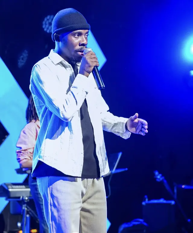Paddy Daniel singing with his hand open under blue light